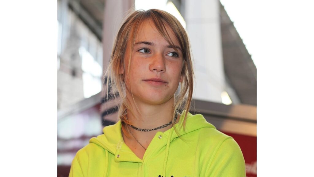 Laura Dekker standing on deck of her yacht Guppy, smiling at camera.