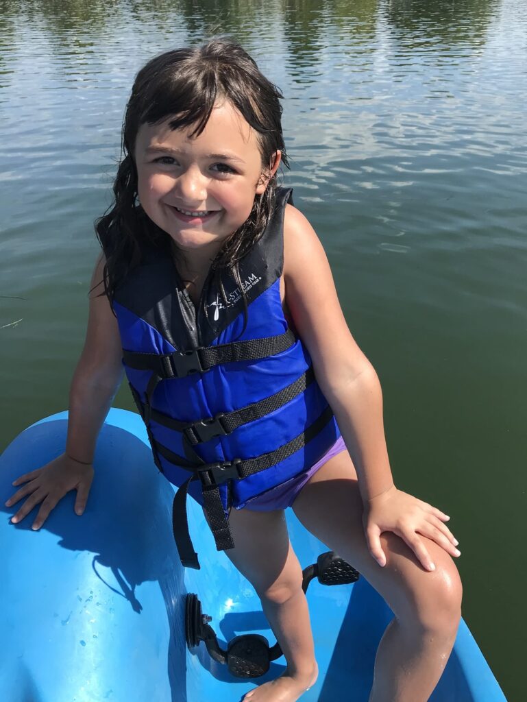 A young child wearin ga life jacket posing aboard a small boat