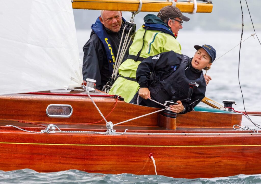 Crew hiking out hard on a classic wooden boat