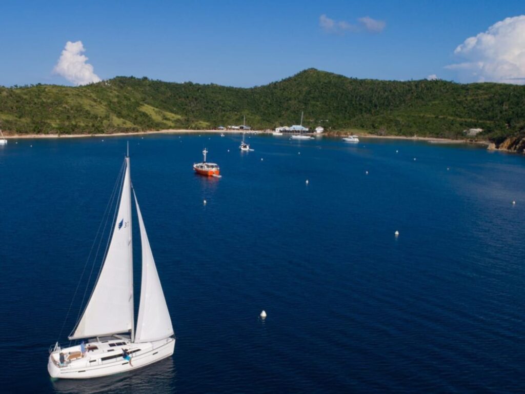 a sailboat approaches an anchorage in the Caribbean