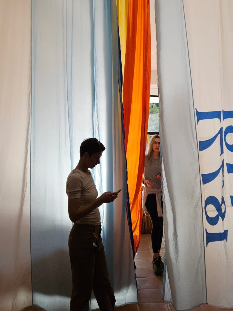 People walking through hanging sails as installation