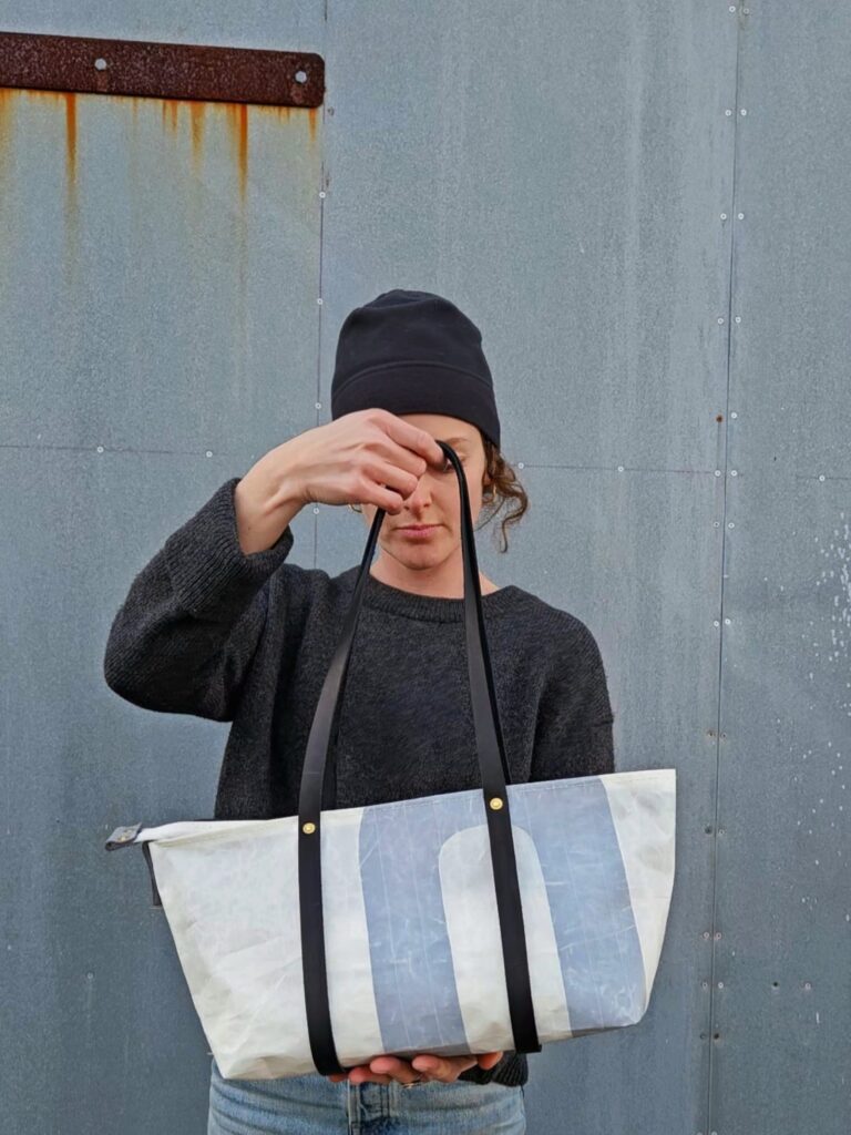 Emma holding large tote in front of metal wall